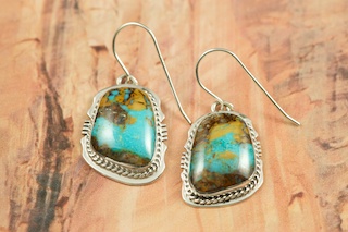 Genuine Sunnyside Turquoise set in Sterling Silver French Wire Earrings. The matrix on this rare stone is outstanding. The Sunnyside mine is located in northern Nevada near the town of Tuscarora in the Tuscarora mountain range. The mine is no longer in operation as it has become part of a gold mining operation and a privately owned ranch. The Sunnyside mine was mined mostly in the 70's. You won't find much of this great turquoise around anymore except for old stashes. Created by Navajo Artist Arkie Nelson. Signed by the artist.